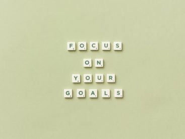 Scrabble letters forming a motivational phrase 'Focus on Your Goals' on a light green background.