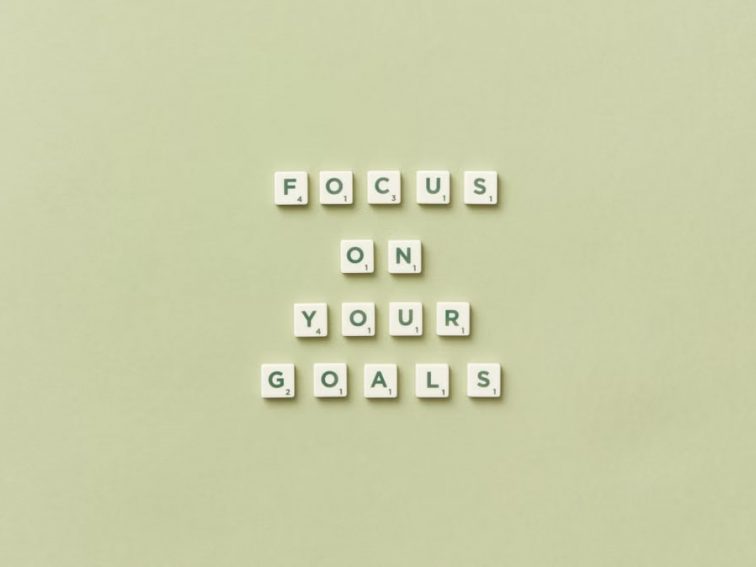 Scrabble letters forming a motivational phrase 'Focus on Your Goals' on a light green background.