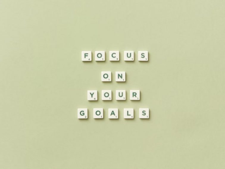 Scrabble letters forming a motivational phrase 'Focus on Your Goals' on a light green background.